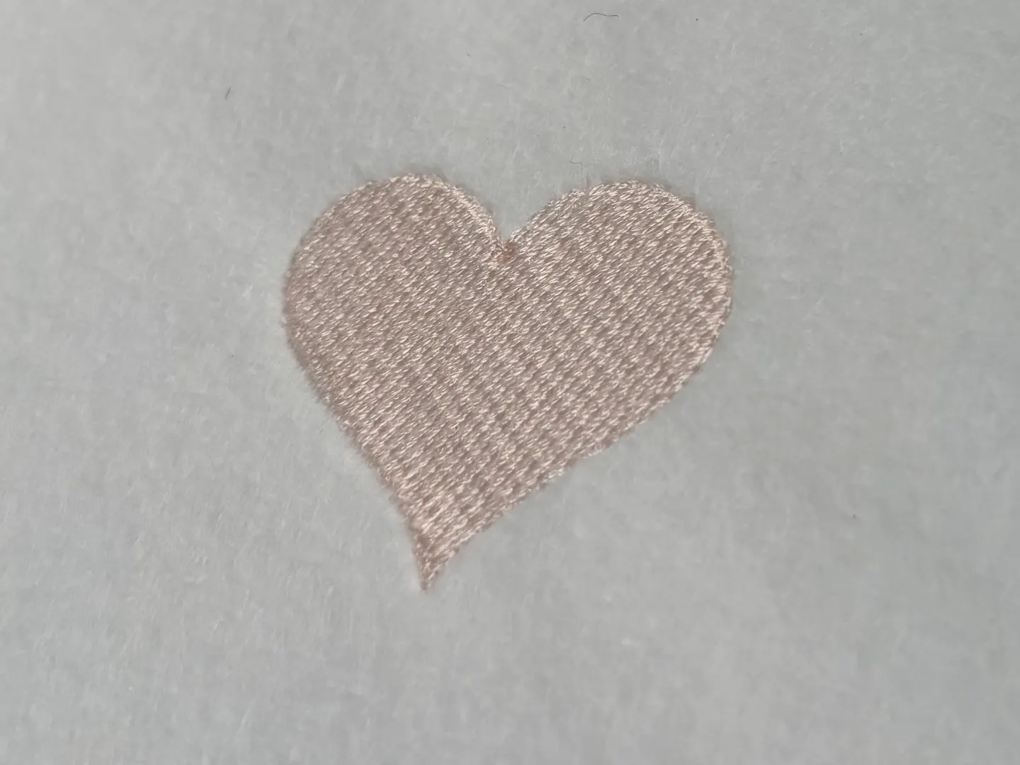The heart from Part 3 close up, the rows of pale pink thread running across it at an angle.